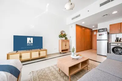 a living room with a couch and a tv at Amazing View Studio Lago Vista IMPZ in Dubai