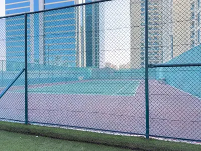 a tennis court behind a chain link fence at Amazing View Studio Lago Vista IMPZ in Dubai