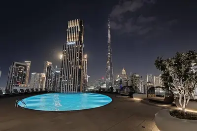 a swimming pool with a city skyline at night at Ultra-Luxury Apartment | Burj Khalifa Skyline Pool in Dubai