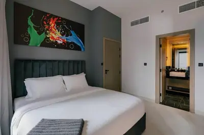 a bedroom with a white bed with a painting on the wall at Luxury 2BR Apt | Infinity Pool with Burj View in Dubai