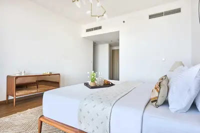 a white bedroom with a bed and a table at Frank Porter - Stella Maris in Dubai