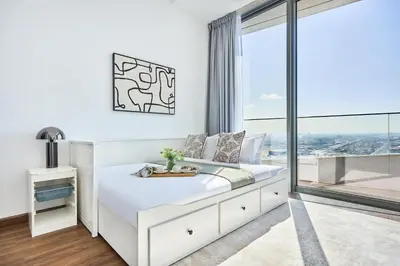 a white bedroom with a bed and a large window at Frank Porter - Stella Maris in Dubai