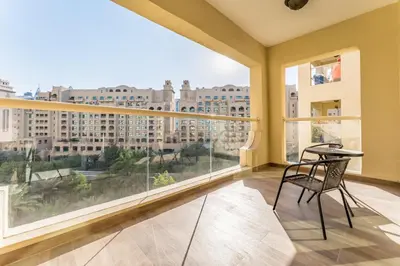 a balcony with a table and a view of buildings at Exclusive Waterfront Residence with Private Beach Access, Near Palm Jumeirah Mall and Restaurants - Jash Hamad Shoreline B18, Palm Jumeirah by Deluxe Holiday Homes in Dubai