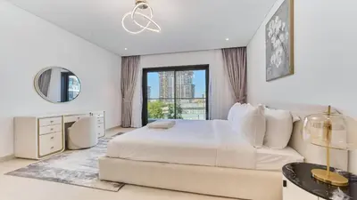 a white bedroom with a large bed and a window at Contemporary 2BR in Central Park Viridian in Dubai