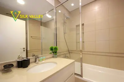 a bathroom with a sink and a tub and a mirror at Silk Valley - Luxury Studio with Pool View - Walk to Park in Dubai