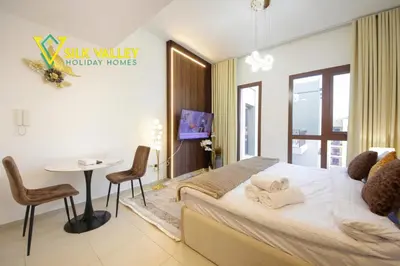 a bedroom with a bed and a table and chairs at Silk Valley - Luxury Studio with Pool View - Walk to Park in Dubai