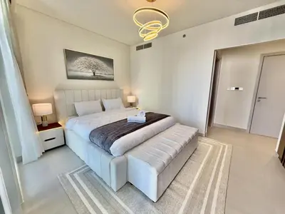 a bedroom with a king sized bed with a tufted foot board at BRAND NEW 2 BDR apartment with beach access in Dubai