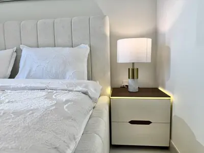 a white bed with a lamp on a night stand at BRAND NEW 2 BDR apartment with beach access in Dubai