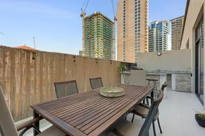 a wooden table and chairs on a balcony with buildings at Urban Chic 1 Bedroom with big Balcony Kitchen in JVC in Dubai