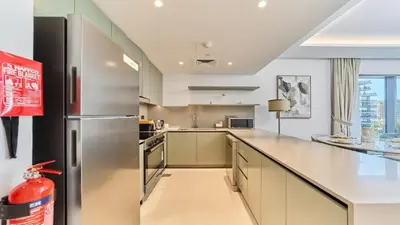 a kitchen with a stainless steel refrigerator and a counter at Modern 2BR in Viridian Central Park City Walk in Dubai