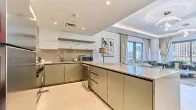 an open kitchen with stainless steel appliances and a living room at Modern 2BR in Viridian Central Park City Walk in Dubai