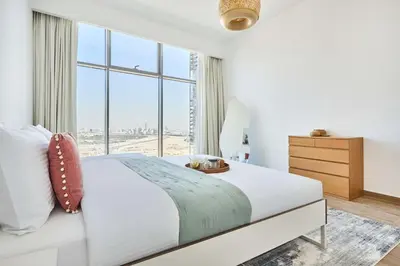a white bedroom with a large bed and a window at Frank Porter - Mada Residences in Dubai