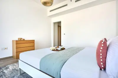 a white bedroom with a bed and a dresser at Frank Porter - Mada Residences in Dubai