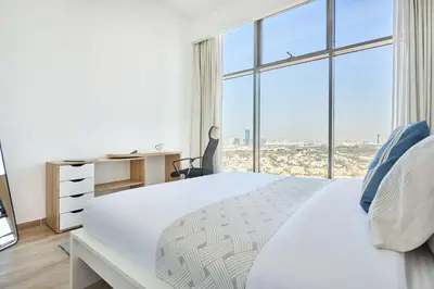 a bedroom with a white bed with a large window at Frank Porter - Mada Residences in Dubai