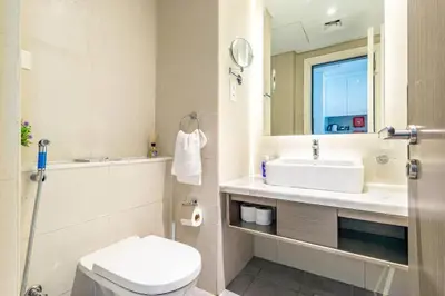 a bathroom with a sink and a toilet and a mirror at Modern Studio in Business Bay - Canal & City Views - Gym & Pool in Dubai