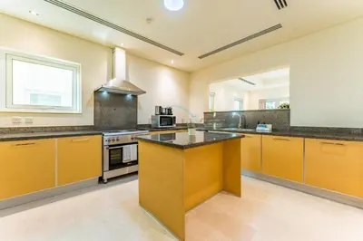 a large kitchen with yellow cabinets and a stove at Spacious 3BR and Assistant Room with Community View - Al Quortaj Villa, Al Furjan by Deluxe Holiday Homes in Dubai