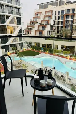 a balcony with a table and chairs and a pool at Deluxe Studio for Rent in Oxford Gardens Dubai in Dubai