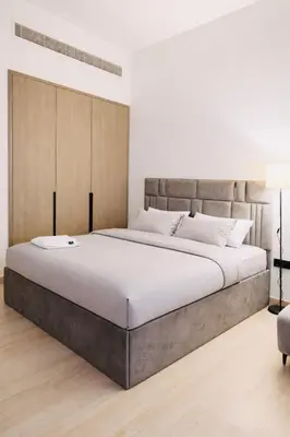 a bedroom with a large bed with a large headboard at Deluxe Studio for Rent in Oxford Gardens Dubai in Dubai
