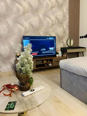 a living room with a tv and a table with a plant at Deluxe Studio for Rent in Oxford Gardens Dubai in Dubai