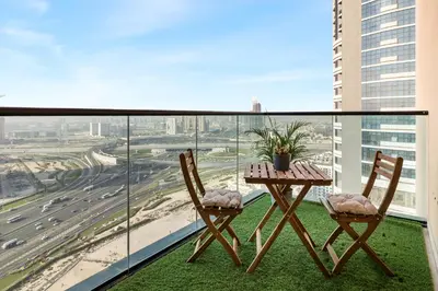a table and chairs on a balcony with a view of a highway at Relaxing Studio with Balcony & Pool at The Square Tower in Dubai
