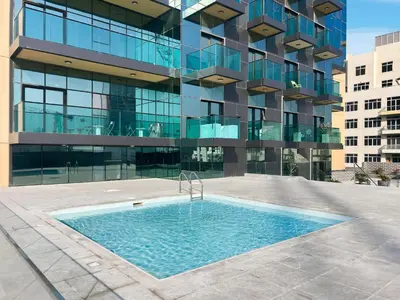 a swimming pool in front of a building at Relaxing Studio with Balcony & Pool at The Square Tower in Dubai