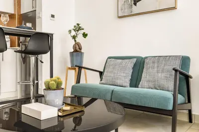 a living room with a couch and a table at Relaxing Studio with Balcony & Pool at The Square Tower in Dubai