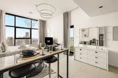 a kitchen with a table with chairs and a counter at Relaxing Studio with Balcony & Pool at The Square Tower in Dubai