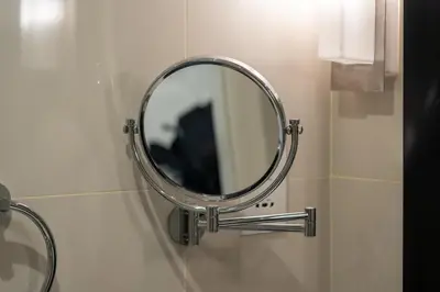 a round mirror on a wall in a bathroom at DAMAC COUR JARDIN - Near Metro - Free Parking in Dubai