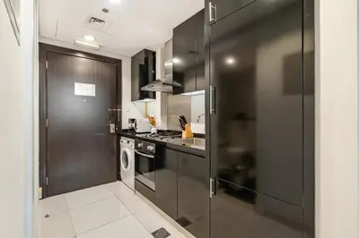 a kitchen with black cabinets and a stove top oven at DAMAC COUR JARDIN - Near Metro - Free Parking in Dubai
