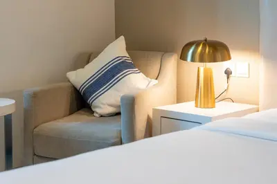a room with a bed and a chair and a lamp at DAMAC COUR JARDIN - Near Metro - Free Parking in Dubai