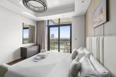a white bedroom with a large bed and a window at Modern 2BR at Nobles Tower Near Downtown in Dubai