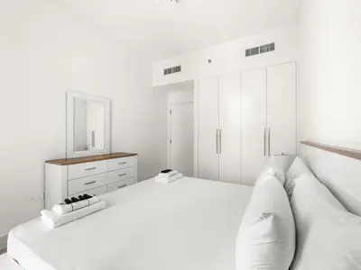 a white bedroom with a bed and a mirror at Breathtaking 1 BDR w Partial Burjkhalifa View in Dubai