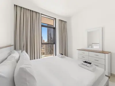 a white bedroom with a large white bed and a window at Breathtaking 1 BDR w Partial Burjkhalifa View in Dubai