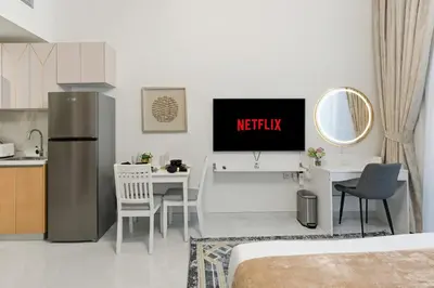 a kitchen with a tv and a table in a room at Modern Studio on 27th Floor with Miracle Garden Views in Dubai