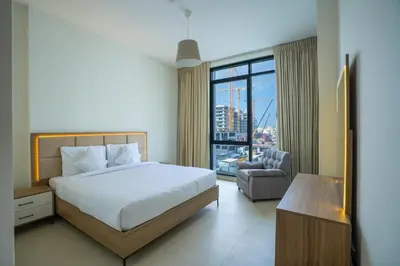 a bedroom with a bed and a chair and a window at Speedway Vacation Homes Rental LLC in Dubai