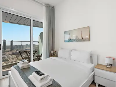 a bedroom with a white bed and a large window at Spacious Studio w Sofa Bed Sleeps 4 in JVC in Dubai