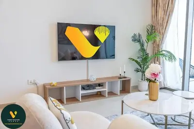 a living room with a tv and a table at Vogue Downtown Views II with Direct Access to Dubai Mall Via a Climate Controlled Bridge, One Bedroom Apartment with Balcony and City View in Dubai