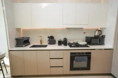 a kitchen with white cabinets and a stove top oven at Bright 1-Bed with Pool and Gym in Dubai