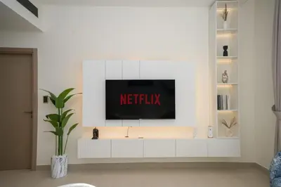 a living room with a television on a white wall at Bright 1-Bed with Pool and Gym in Dubai