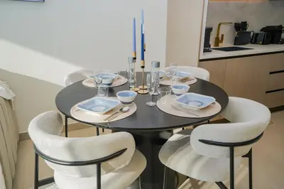 a dining room table with four chairs and a black table at Bright 1-Bed with Pool and Gym in Dubai