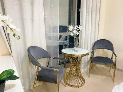 a table and two chairs and a vase with flowers at Enjoy Studio in Dubai Marina - Partial Marina View in Dubai