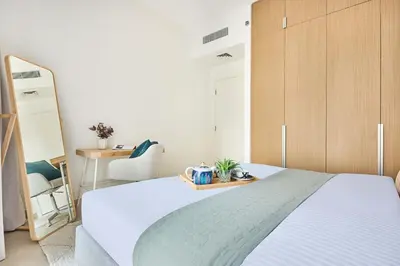 a bedroom with a white bed and a wooden cabinet at Frank Porter - Grove at Creek Beach Building in Dubai