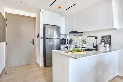 a kitchen with white cabinets and a stainless steel refrigerator at Frank Porter - Binghatti Corner in Dubai