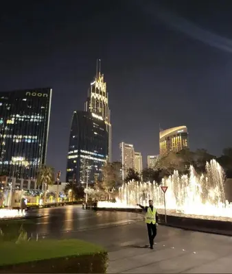 a person walking in front of a fountain at night at Stunning Apartment - Downtown View 2 - Tower 1 - Fountain and Burj Khalifa view 61st floor in Dubai