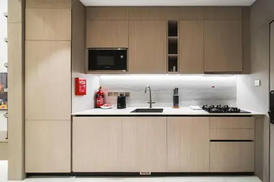 a kitchen with wooden cabinets and a sink at SettlerHomes - Chic JVC Studio - Pool & Clubhouse in Dubai