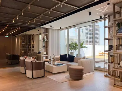 a living room with couches and chairs and windows at SettlerHomes - Chic JVC Studio - Pool & Clubhouse in Dubai