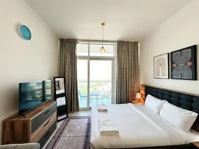 a bedroom with a large bed and a television at Cozy Studio Retreat in Damac Hills in Dubai