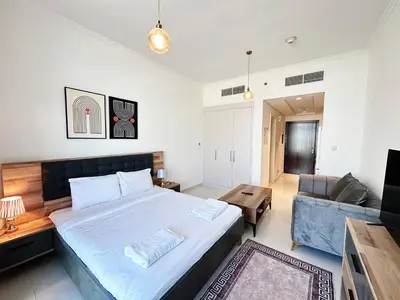 a bedroom with a large bed and a couch at Cozy Studio Retreat in Damac Hills in Dubai