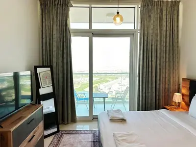a bedroom with a bed and a large window at Cozy Studio Retreat in Damac Hills in Dubai