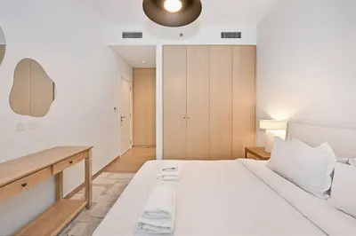 a bedroom with a white bed and a desk at Belgravia Heights 1 BHK in JVC in Dubai